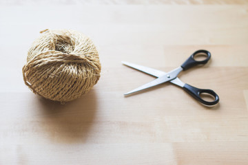 A top angle of a decorative hemp rope on wooden table with black scissor