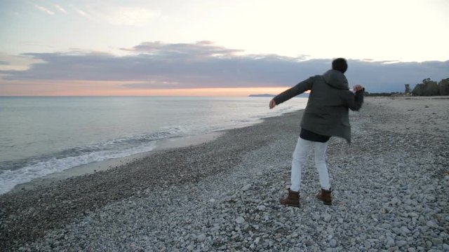 Ragazzo arrabbiato che lancia sassi nel mare