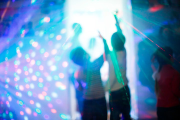 Fototapeta na wymiar Children at a disco during the laser show with colorful rays lig