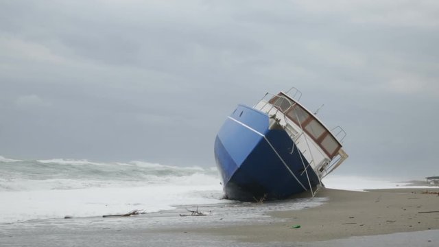 Nave arenata sulla spiaggia con le onde che si infrangono su di essa