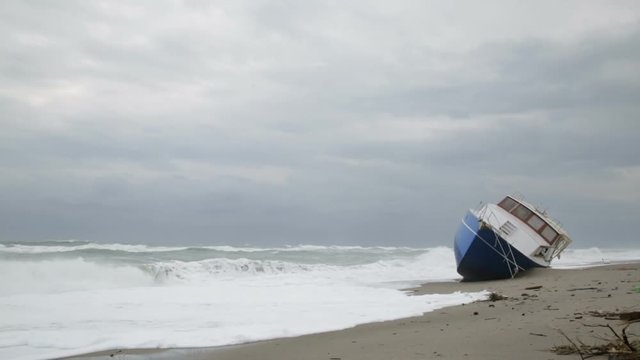 Nave arenata sulla spiaggia con le onde che si infrangono su di essa