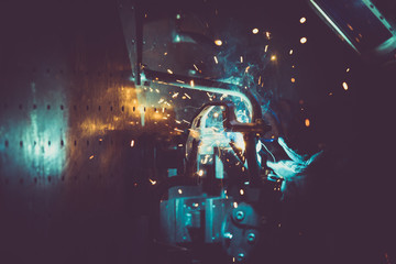 Metal welding with sparks, reflections by industrial worker