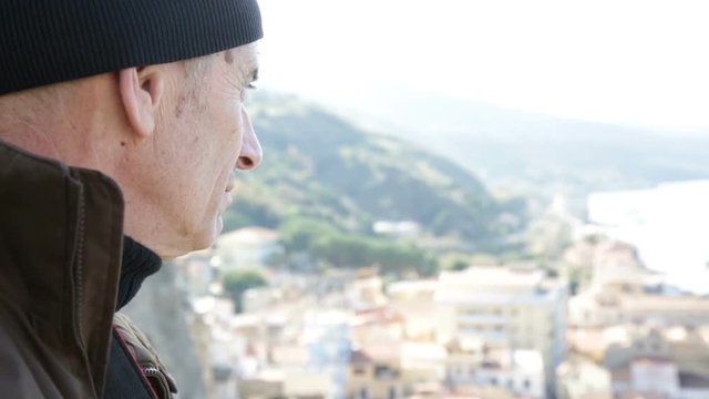 Signore con cappello invernale nero sta guardando il panorama di un paese dall'alto