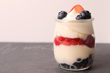 Creamy dessert with berries, raspberries, blueberries strawberries on the stone slate board
