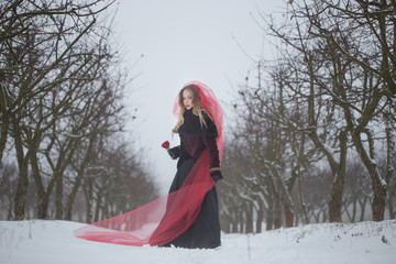 Fototapeta na wymiar girl in a red veil on the snow in the winter