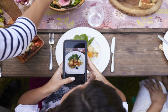 Guest Taking Picture Of Food On Mobile Phone At Party