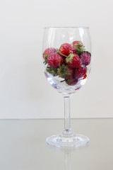Strawberry berries in a glass of wine on the table.