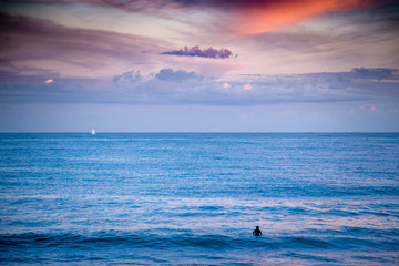 Fototapeta premium Surfer and the yacht with sail in the open Sea at the sunset. 