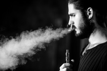 young bearded hipster man smokes electronic cigarette. 