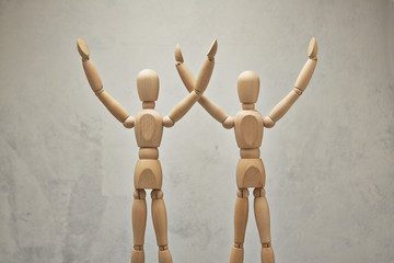 Two wooden mannequin hands up as winners