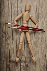 Wooden mannequin with paintbrush