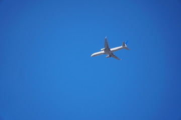 Passenger jet airline flying overhead. Airplane heading towards international airport for landing on clear blue sky sunny day.