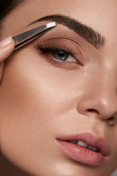 Beauty Woman Makeup. Closeup Of Beautiful Glamorous Sexy Woman Face With Smooth Skin Plucked Eyebrows And Metal Tweezers. Young Female Model Shaping Brows. Beauty And Skin care. High Resolution