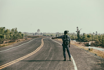 Man hitchhiker standing on a road. Adventure and tourism concept