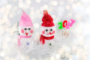 Two toy snowman with festive Christmas background