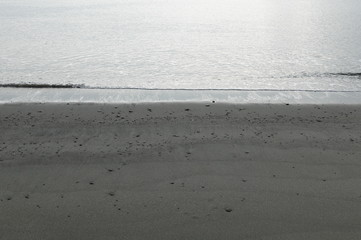薄雲りの静かな海　打ち上げられた小石と小波