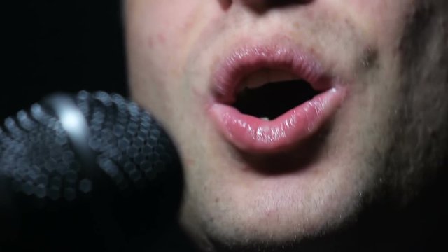 Close-up of man singing to microphone in dark
