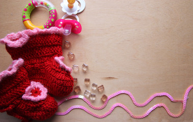 Детские сапожки, соска и погремушка на деревянном фоне 