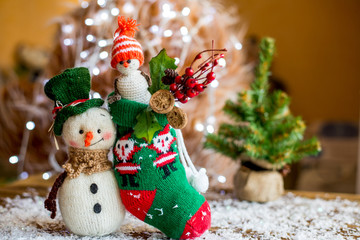 Handmade yarn snowman holding gifts in a sock, boot.