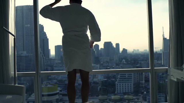 Happy man in bathrobe dancing by window at home, super slow motion 240fps
