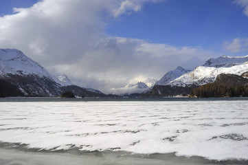 Fototapeta na wymiar Engadin valley in Switzerland Sils Maria village with snow on Alp mountains and frozen lake