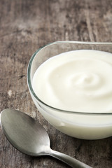 Greek yogurt in glass bowl on wooden table
