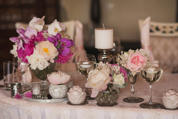 Table setting at wedding reception. Floral compositions and candles on decorated dining table.