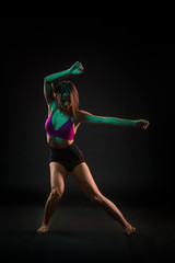 Young beautiful dancer in beige dress dancing on black background