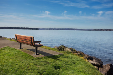 Fototapeta na wymiar Bench at a lakeside park overlooking Lake Washington in Spring sunshine