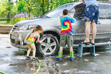 Family car wash - Brother & sister help Dad with washing a car in the driveway