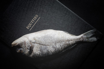 Raw fresh fish on shares equities prices letters background as m