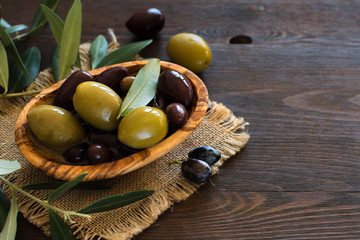 Olives in a bowl on wood background