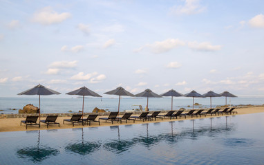 Beautiful luxury umbrella and chair around outdoor swimming pool in hotel resort neary sea and beach - Boost up color Processing style