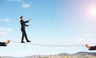 Business concept of risk support and assistance with man balancing on rope