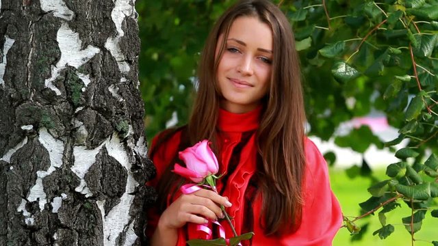 Beautiful girl posing with rose in the park.
