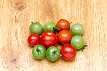 Red and green tomatoes on the background of natural wood.