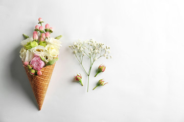Waffle cone with composition of flowers and branches on white background