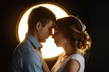 loving man and woman in the rays of light on a black background