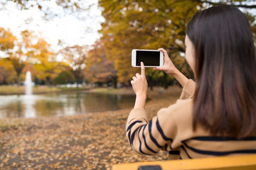 Woman taking photo at park in autumn season