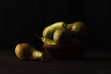 Green pears on wooden table dark background, front view