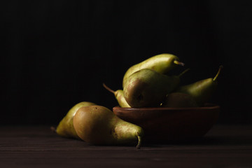 Green pears on wooden table dark background, front view
