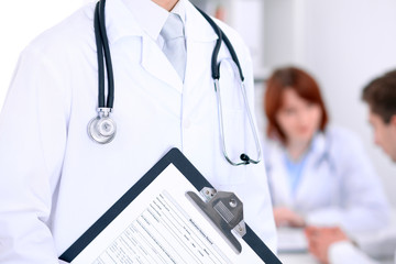 Close-up of a male doctor in a background of doctor and patient