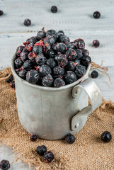 Fototapeta na wymiar Rustic old mug with frozen blueberries and currants, on white wooden table
