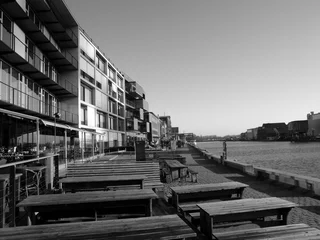 Tische und Bänke aus massivem Holz vor einem Restaurant und Bistro am Kreativkai an der Hafenpromenade am Hafen von Münster in Westfalen im Münsterland, fotografiert in neorealistischem schwarzweiß © Martin Debus