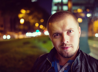 Handsome young hipster outside in the night city