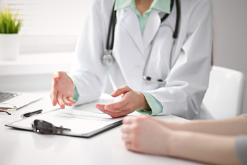 Fototapeta premium Close up of doctor and patient sitting at the desk near the window in hospital