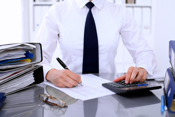 Bookkeeper or female financial inspector  making report, calculating or checking balance. Internal Revenue Service checking financial document. Audit concept.