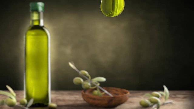 Drop of oil and bottle of olive oil with branch in the background