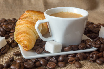 Cup and grain of coffee over textile background