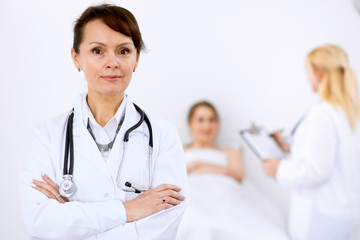 Fototapeta premium Female doctor smiling on the background with patient and his doctor